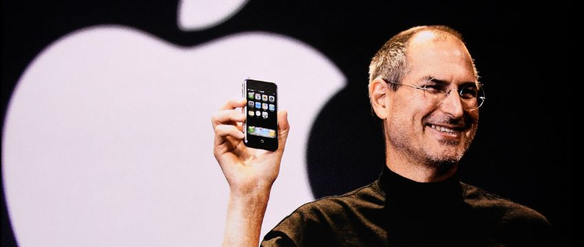 Steve Jobs líder de Apple sonriendo y presentando un iPhone